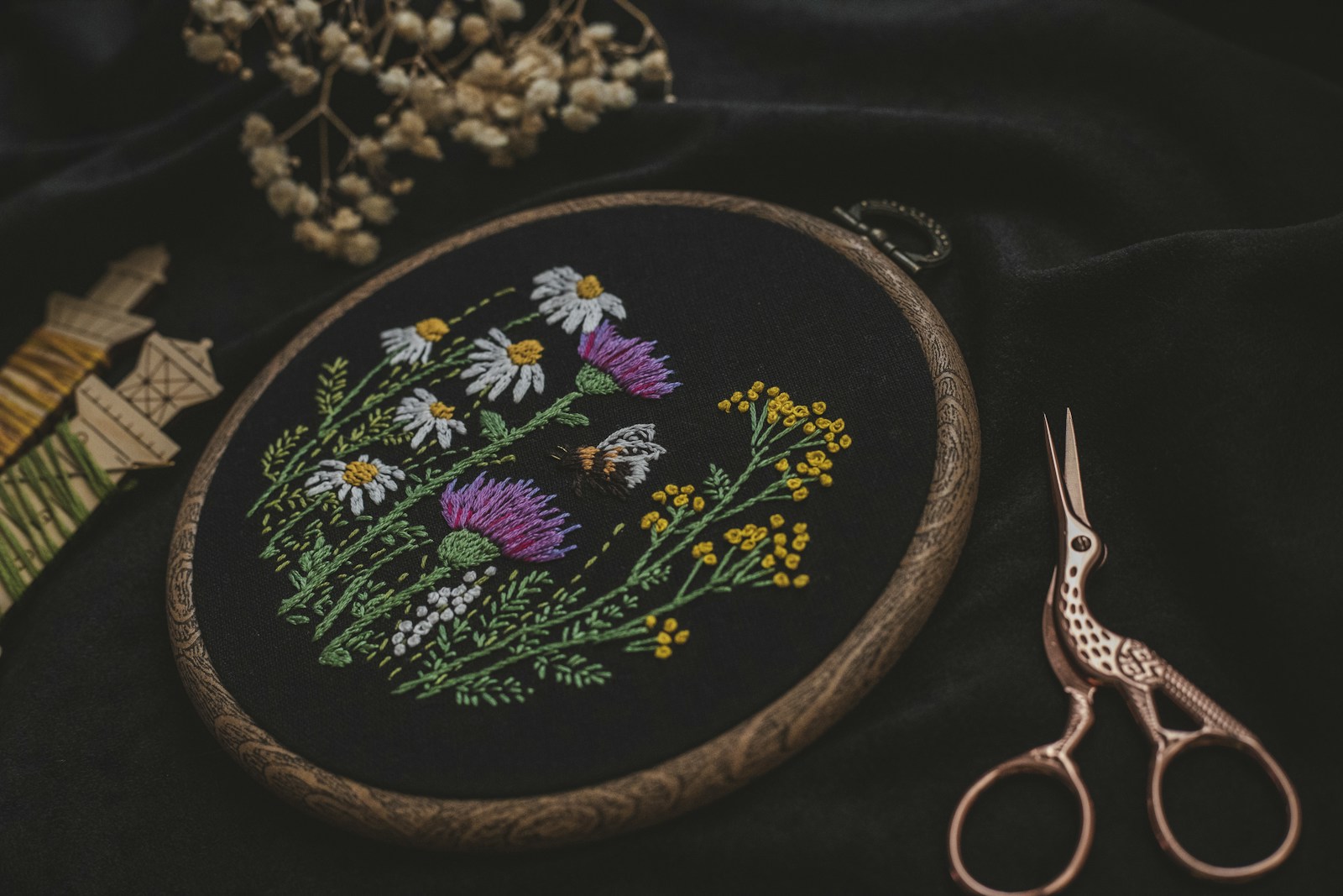 Photo by Ksenia Yakovleva a close up of a embroidery on a black cloth with a pair of scissors